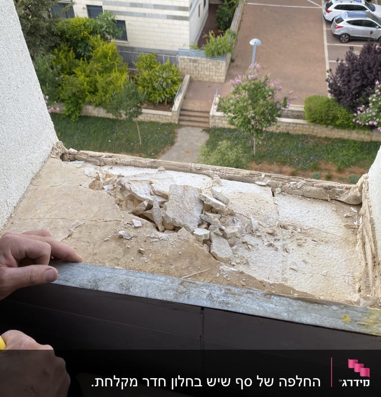 אדם מחזיק פטיש ליד חלון עם טיח מתפורר